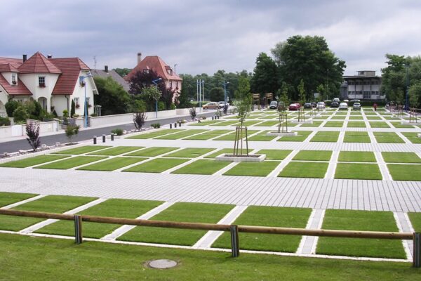 Weitläufiger Parkplatz mit begrünten Flächen und Pflasterabtrennungen in einem Wohngebiet