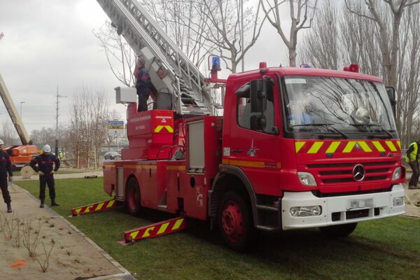 Feuerwehrauto steht auf grüner ECORASTER Fläche mit Rettungskräften an der linken Seite