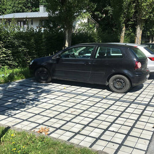 Autos auf Parkplätzen aus ECORASTER Bloxx Modulen, im Hintergrund Bäume und Hecken