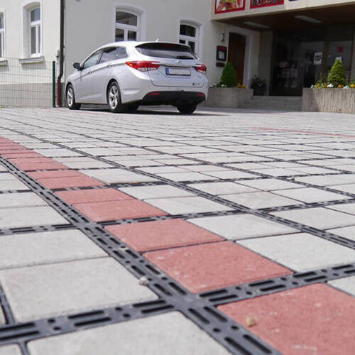Nahe Ansicht eines ECORASTER Bloxx Parkplatzes mit Auto und Metzgerei im Hintergrund