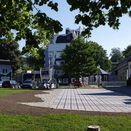 ECORASTER Bloxx Parkplätze umgeben von Häusern, grüner Rasenfläche und Bäumen