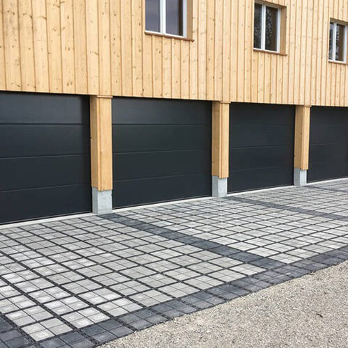 Fertige ECORASTER Bloxx Parkplätze, vor fünf Garagen in einem Holzbau
