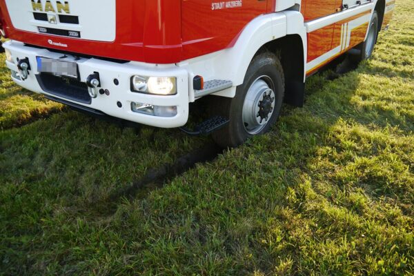 Feuerwehrauto steht auf einer Wiese und ist eingesunken