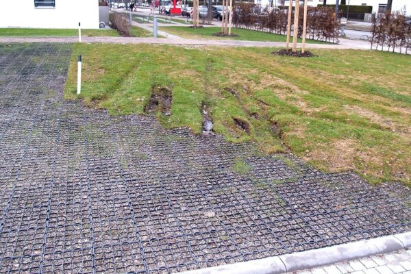 Mit Kies befüllte ECORASTER Feuerwehrzufahrt im Kontrast zu matschigen Spuren einer nicht-befestigten Fläche