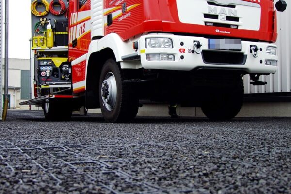 Feuerwehrauto steht auf mit dunklem Splitt befüllten ECORASTER