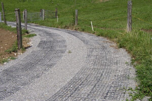 Mit Schotter verfüllter ECORASTER Weg führt um eine Kurve