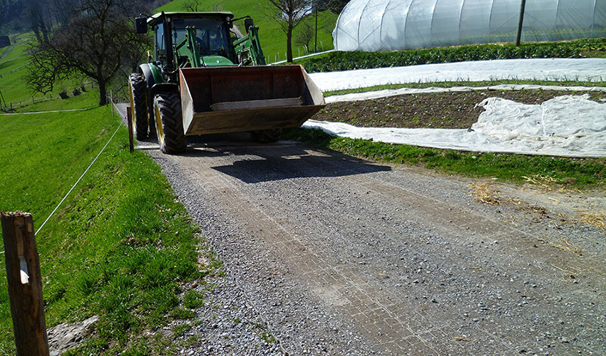 Ein Traktor fährt auf einer mit ECORASTER befestigten Zufahrt